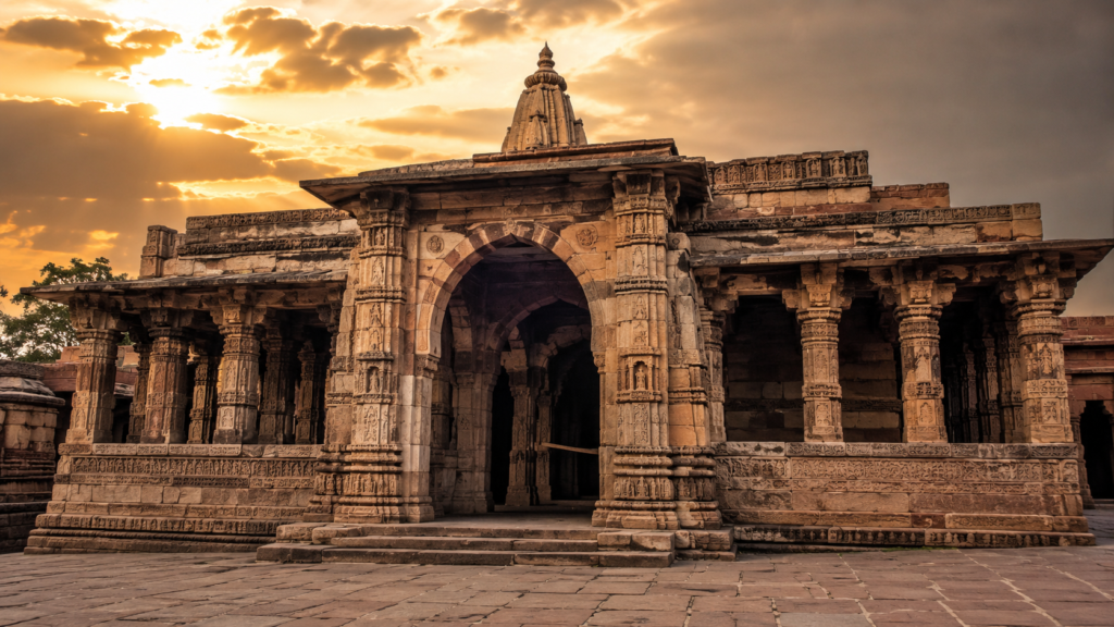 भोजशाला विवाद पर लेख के लिए प्राचीन पत्थर के मंदिर जैसी ऐतिहासिक इमारत, नक्काशीदार स्तंभों और सुनहरे आसमान के साथ दिखाई गई प्रतीकात्मक तस्वीर।